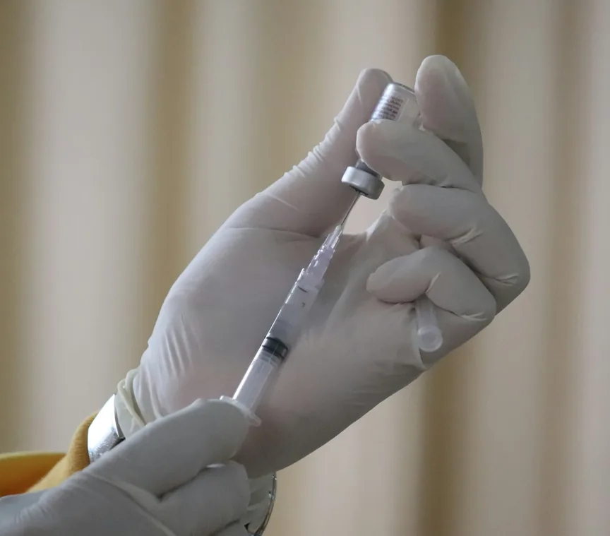 Gloved hands preparing a syringe